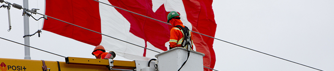 Hydro Ottawa's power line technician working with Canada's flag behind