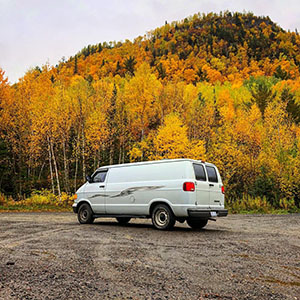 White van with autumn trees in background